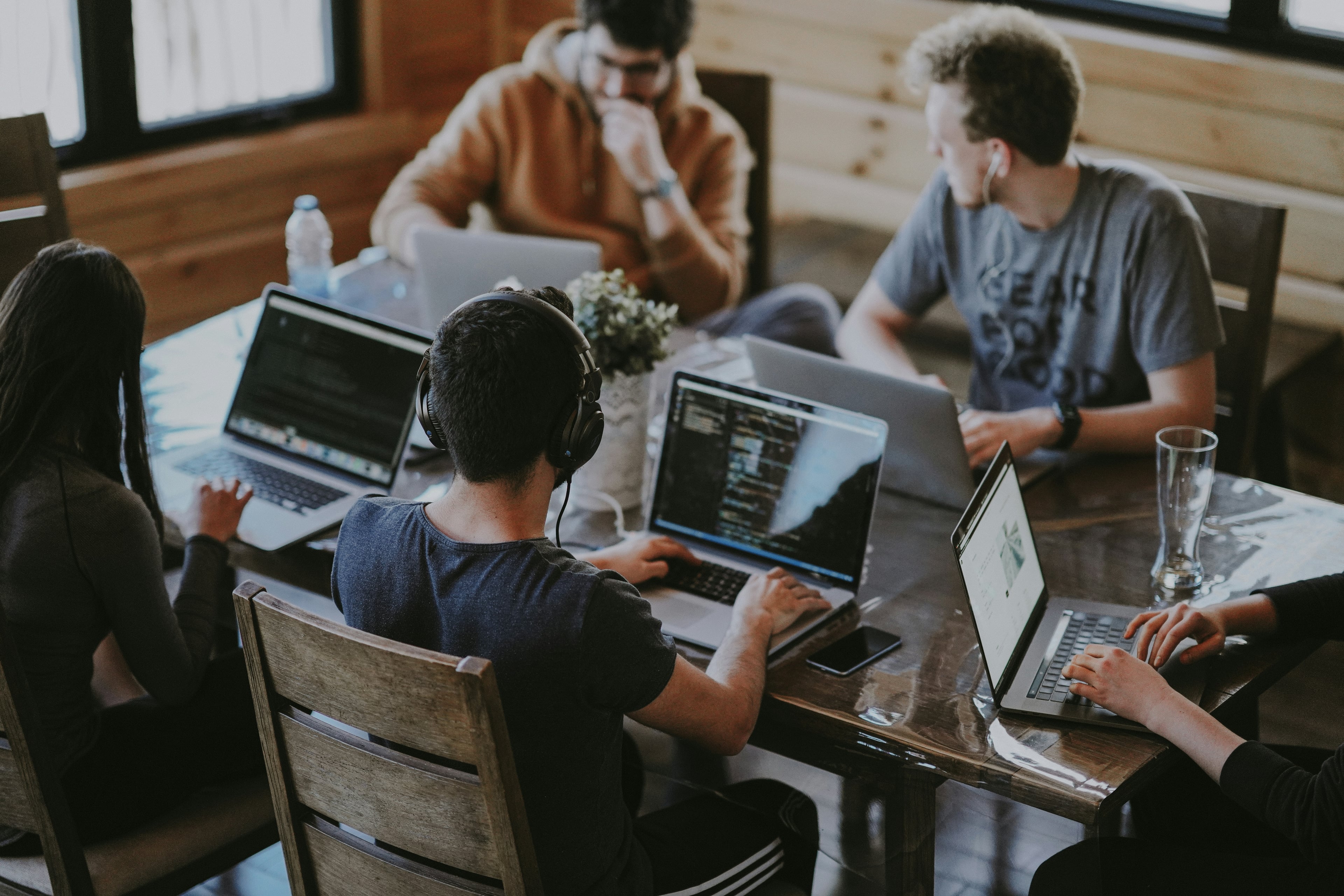 B2B SaaS team in conversation at a workstation, code visible on a large monitor in a bright modern office.